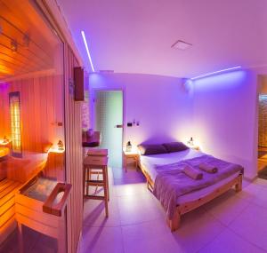 una camera da letto con illuminazione viola, un letto e uno sgabello di Savna cimr a Mežica