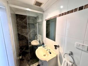 een witte badkamer met een wastafel en een douche bij 2 Bedroom 2 Bathroom Apt with Balcony and Parking in Sydney