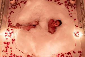 a man laying in a bath tub with foam at Estalagem Spiller in Monte Verde