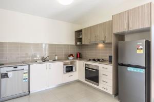a kitchen with white cabinets and a refrigerator at 2 Bedroom w/Parking Near Central Cessnock in Cessnock