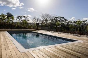a swimming pool in front of a fence at Plume Villas in Matakana
