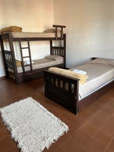 2 Etagenbetten in einem Zimmer mit einem weißen Teppich in der Unterkunft Casa Ciao in Deán Funes
