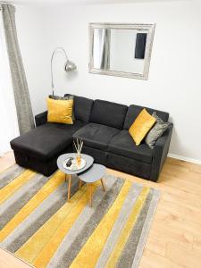 a black couch in a living room with a table at Beautiful apartment in Beckton with Private Entrance and Garden in London