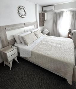 um quarto com uma cama grande com lençóis brancos e almofadas em Hotel Plaza Formosa em Formosa