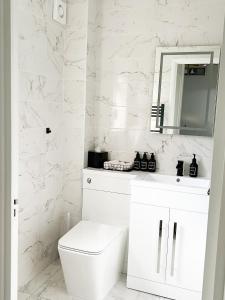 une salle de bain blanche avec toilettes et miroir dans l'établissement Beautiful apartment in Beckton with Private Entrance and Garden, à Londres 19 autres photos