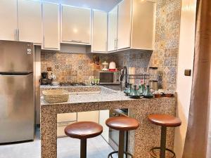 una cocina con armarios blancos y taburetes marrones. en Villa Charfa Élégance Confort et Vues Panoramiques en Esauira