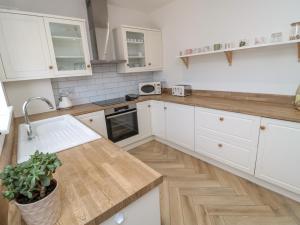 eine Küche mit weißen Schränken und einer hölzernen Arbeitsplatte in der Unterkunft The Miners Cottage in Berwick-Upon-Tweed