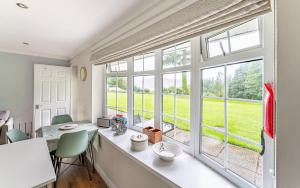 een eetkamer met ramen en een tafel en stoelen bij Lowera Cottage in Windermere