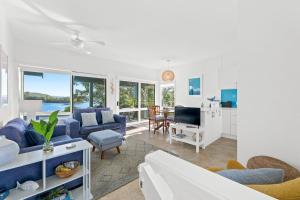 a living room with blue furniture and a view of the ocean at 4-53 Forsters Bay Road, Narooma - Blue Water Villas in Narooma