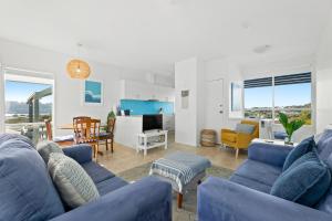 a living room with blue couches and a kitchen at 4-53 Forsters Bay Road, Narooma - Blue Water Villas in Narooma