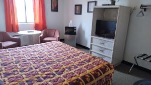 - une chambre avec un lit et une commode avec une télévision dans l'établissement Northgate Inn Motel, à Challis