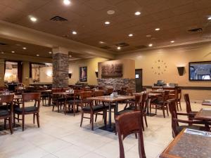 un restaurante con mesas y sillas de madera y TV en Carriage House Hotel and Conference Centre, en Calgary