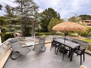 een patio met een tafel en stoelen en een rieten parasol bij APPART Tropez 1 in Saint-Tropez