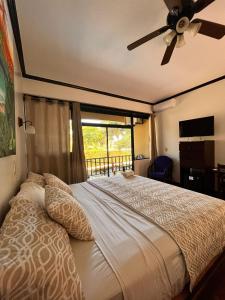 1 dormitorio con 1 cama grande y ventilador de techo en The Backyard Beachfront Hotel, en Jacó