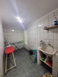 a bathroom with a sink and a red stool at Casa com dois quartos,dois banheiros,sendo uma suíte,sala de estar cozinha e garagem in Poços de Caldas