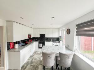 uma cozinha com armários brancos e uma mesa e cadeiras em Beautiful Newly Renovated House in Rainham Essex em Rainham