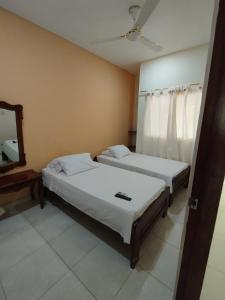 2 camas sentadas en una habitación con espejo en Hostal Doña Nancy en Mompox