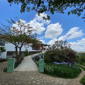 a walkway in front of a house with a tree at Quinta Vogrande no bairro de Águas Santas entre Tiradentes e São João Del Rey in Tiradentes