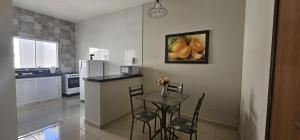 een keuken met een tafel en een schilderij van fruit aan de muur bij Casa Duplex Alegria - Ar e Garagem Privativa in Bom Jesus da Lapa