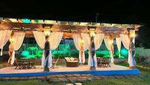 a gazebo with white curtains and tables and chairs at Casa de Maju in Morros