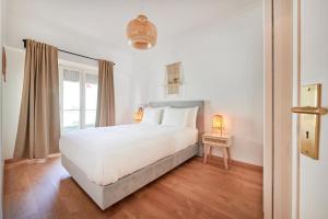 a white bedroom with a white bed and a window at Sunny - Cozy Apartment in Amadora