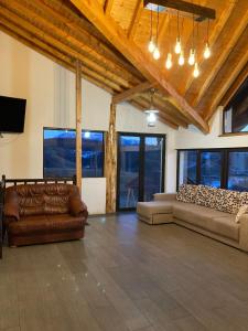 a living room with two couches and a tv at Casa din Livadă, Poiana Mărului, Brasov in Poiana Mărului