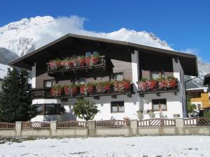 a building with flower boxes in front of a mountain at Ferienheim Leopoldine in Längenfeld