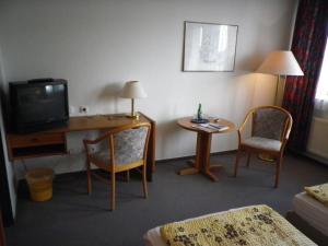 a hotel room with a desk with a tv and chairs at Stadthotel Oldenburg in Oldenburg