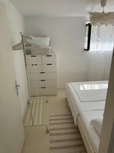 a white bedroom with a bed and a dresser at Apartmani Krk in Krk