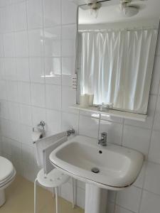 a white bathroom with a sink and a mirror at Apartmani Krk in Krk