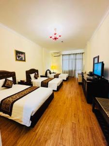 um quarto de hotel com três camas e uma televisão de ecrã plano em Ngọc Lan Hotel em Ho Chi Minh