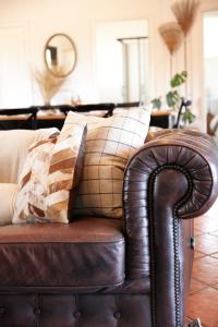 a brown leather couch with two pillows on it at The Caretakers Cottage in Belford