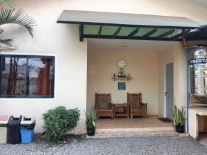 a patio with two chairs and a table and a clock at CG'S TRAVELLERS INN in Panglao