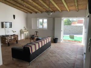 a living room with a bed and a desk and a window at Casa da Oliveira in Mértola
