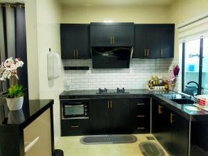 a kitchen with black cabinets and a sink at Homestay No 23 Kuala Krai in Kuala Kerai
