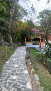 a stone walkway next to a yard with a bench at Casa del Arroyo 2-Bedroom Cottage Fireplace and BBQ in Jarabacoa
