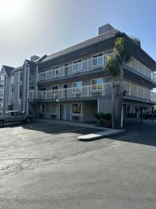 a large apartment building with a palm tree in a parking lot at Motel Santa Cruz in Santa Cruz