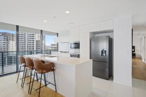 a kitchen with a counter with stools and a refrigerator at Oracle 2 1907 in Gold Coast