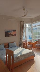 1 dormitorio con 1 cama y algunas sillas y ventanas en Eureka Resort, Hai Tien Beach, en Thanh Hóa