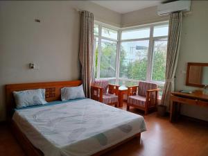 a bedroom with a bed and a desk and a window at Eureka Resort, Hai Tien Beach in Thanh Hóa