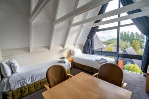 Zimmer mit 2 Betten, einem Tisch und einem Fenster in der Unterkunft Heartland Hotel Queenstown in Queenstown