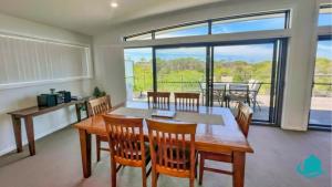 a dining room with a table and chairs and a large window at Beachside Beauty in Caves Beach
