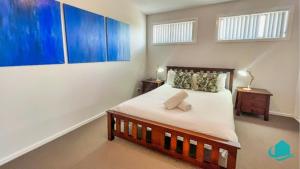 a bedroom with a bed and a painting on the wall at Beachside Beauty in Caves Beach