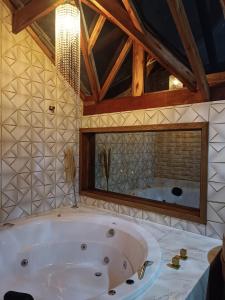 uma grande casa de banho com banheira e espelho em Pousada rota nas montanhas em Camanducaia