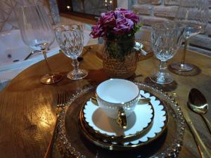 a table with a cup and a plate and wine glasses at Pousada rota nas montanhas in Camanducaia