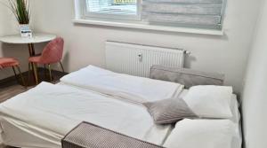 uma cama com lençóis brancos e almofadas num quarto em Ljubljana Central Studio with Free Parking em Ljubljana