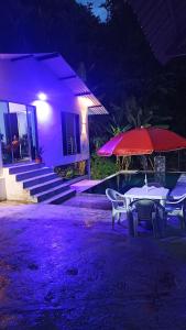 einen Tisch und Stühle mit einem Regenschirm vor einem Haus in der Unterkunft Cabaña Mi Chelita in Ibagué