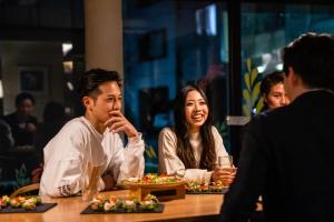 un hombre y una mujer sentados en una mesa con comida en &AND HOSTEL KURAMAE west en Tokio