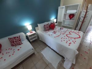 Un dormitorio con una cama con corazones rojos. en Pousada Rosa dos Ventos Juquehy Pet Friendly, en Juquei