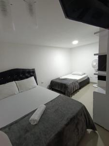 a bedroom with two beds and a tv in it at Hotel Coffee Real Pereira in Pereira